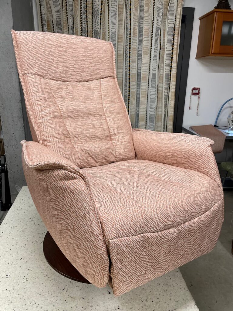 Fauteuil relax inclinable recouvert d'un tissu rose à motif géométrique, réfection à l'atelier tapissier d'Albi