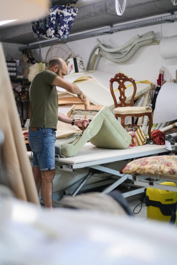 Tapissier d'ameublement travaillant une garniture de siège dans son atelier à Albi