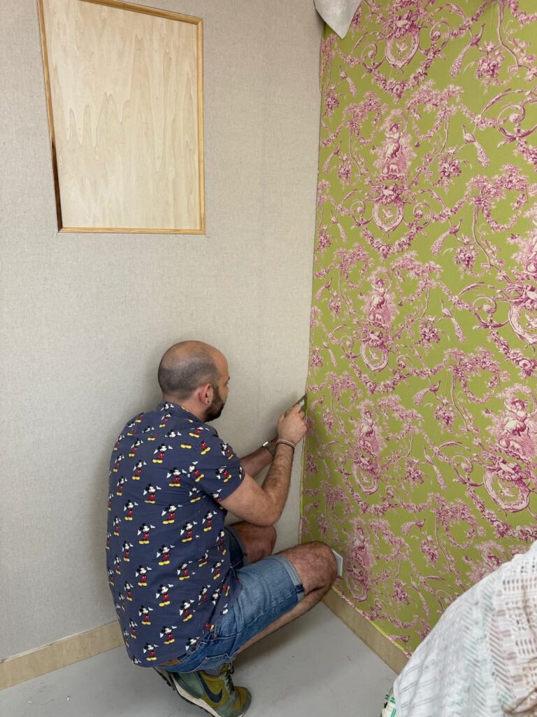 Tapissier posant un tissu tendu mural en toile de Jouy verte et rose dans une pièce à Albi