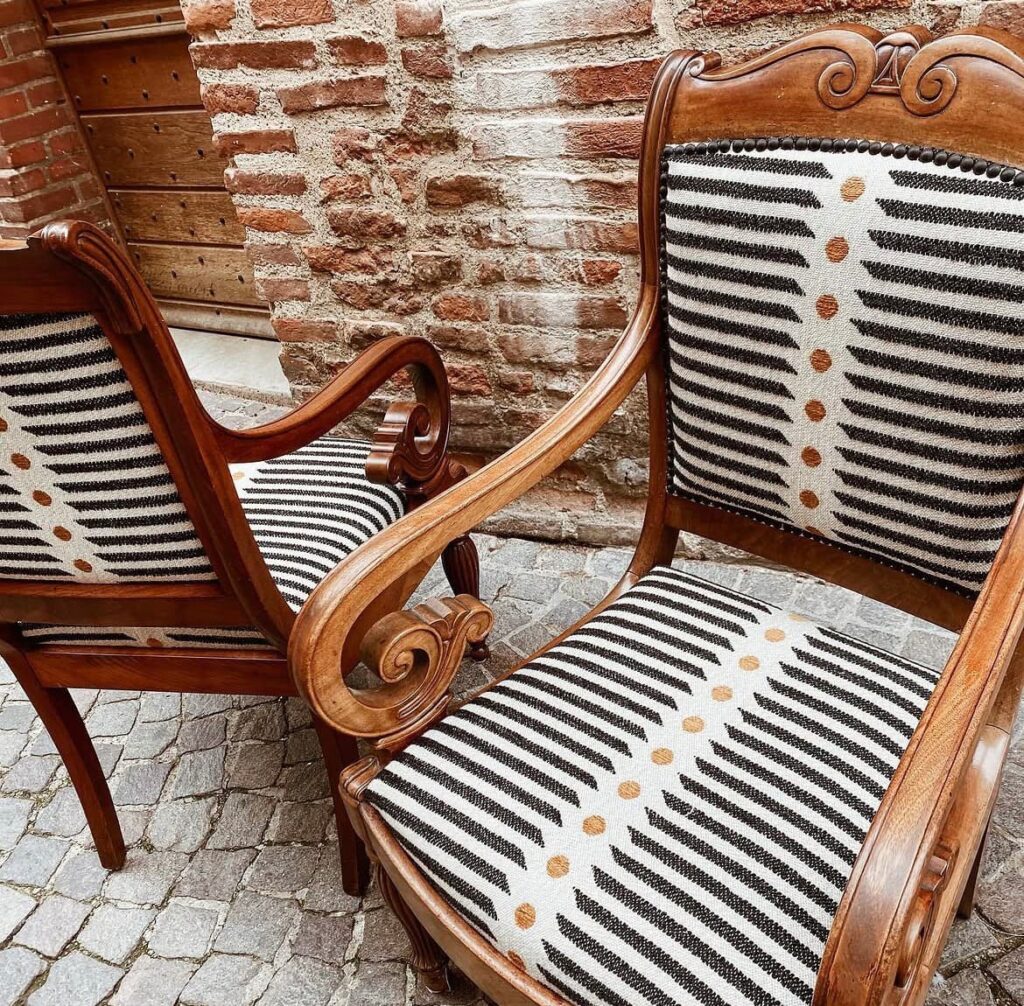 Paire de fauteuils anciens en bois refaits en tissu rayé écru et noir à pois, garnis de clous décoratifs, tapissier Albi