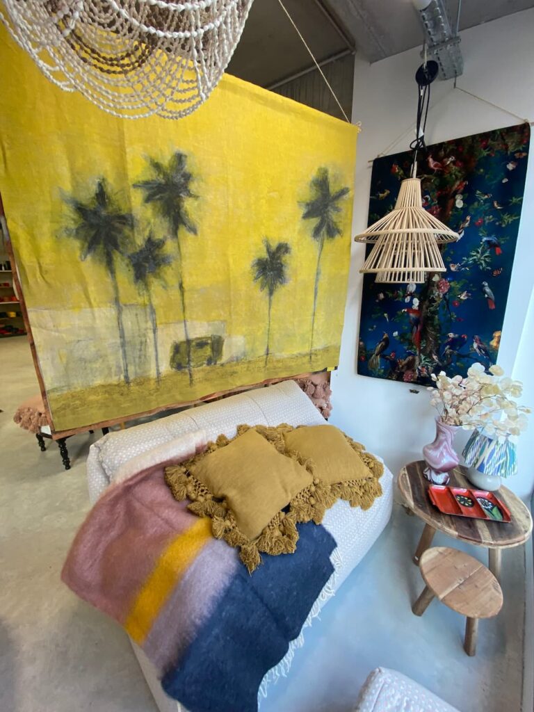 Coin déco avec banquette, coussins à pompons et tentures dans la boutique du tapissier à Albi
